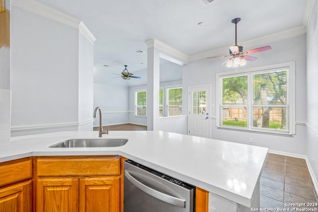 kitchen with brown cabinetry, ornamental molding, light countertops, stainless steel dishwasher, and a sink