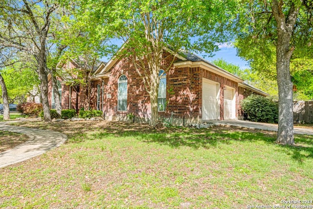 view of front facade featuring a garage, driveway, brick siding, and a front yard