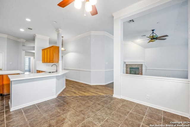 kitchen with light countertops, visible vents, a tiled fireplace, ornamental molding, and a sink