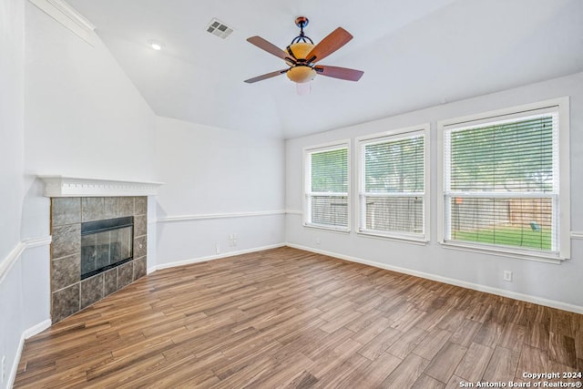 unfurnished living room with lofted ceiling, light wood finished floors, visible vents, and a tiled fireplace