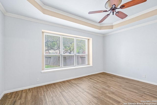 spare room featuring light wood-type flooring, baseboards, and a raised ceiling