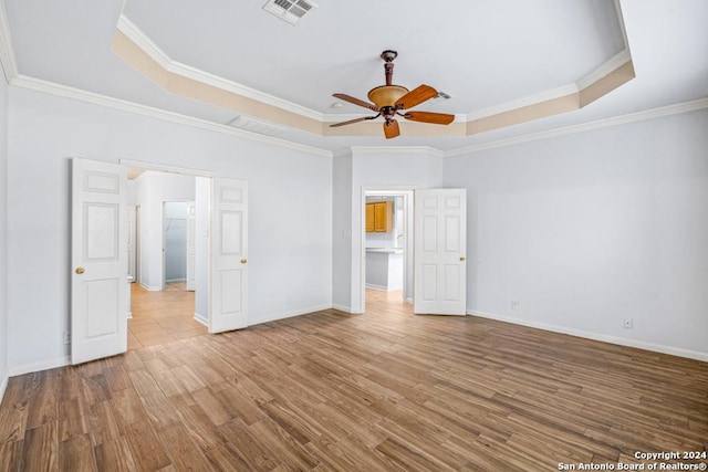 unfurnished bedroom featuring a raised ceiling, visible vents, and wood finished floors