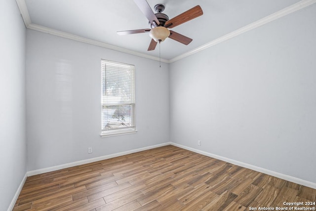 spare room with baseboards, wood finished floors, and crown molding