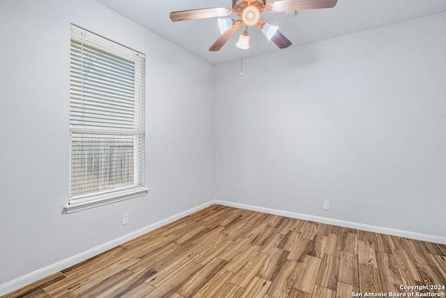 empty room with wood finished floors, a ceiling fan, and baseboards