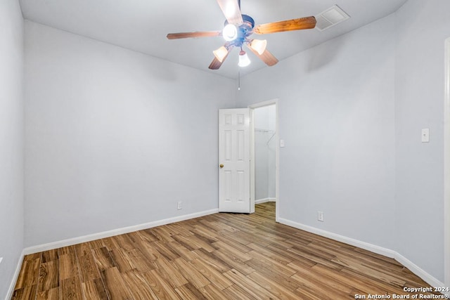 empty room featuring a ceiling fan, baseboards, visible vents, and light wood finished floors