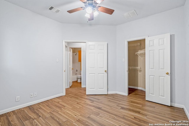 unfurnished bedroom featuring a closet, visible vents, light wood-style flooring, a spacious closet, and baseboards