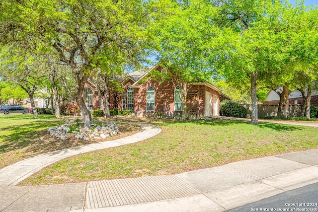 view of front of house featuring an attached garage, fence, a front lawn, and brick siding