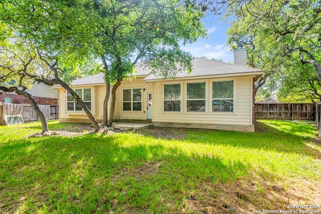 back of property featuring roof with shingles, a lawn, a chimney, and a fenced backyard