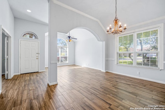 entrance foyer with arched walkways, crown molding, wood finished floors, baseboards, and ceiling fan with notable chandelier