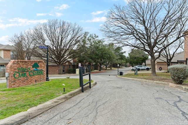 view of road with a gate, street lights, a gated entry, and curbs