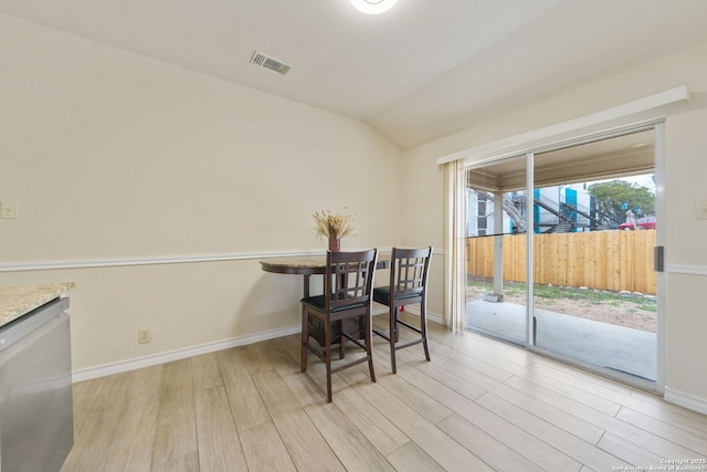 dining space with vaulted ceiling, light wood finished floors, visible vents, and baseboards