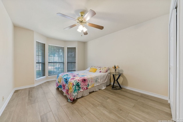 bedroom with a ceiling fan, baseboards, and light wood finished floors