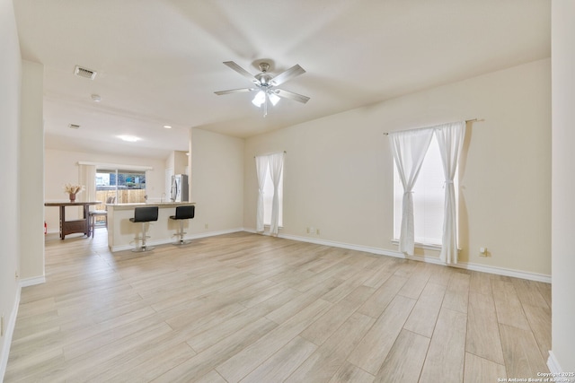 unfurnished living room with ceiling fan, light wood-type flooring, visible vents, and baseboards