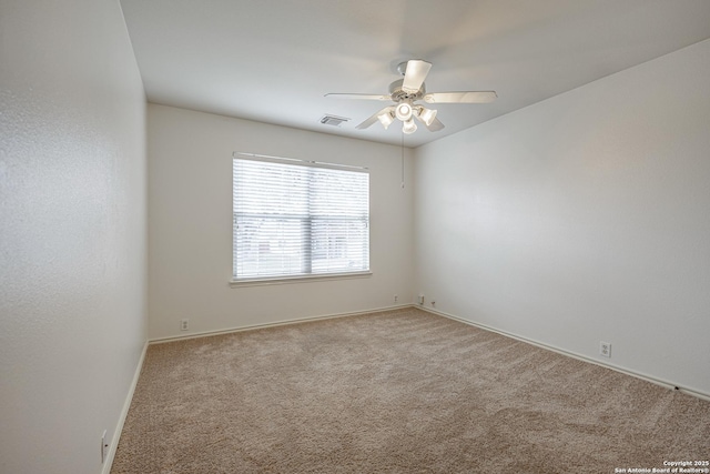 carpeted spare room with baseboards, visible vents, and ceiling fan