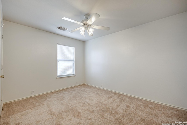 carpeted spare room featuring a ceiling fan and visible vents