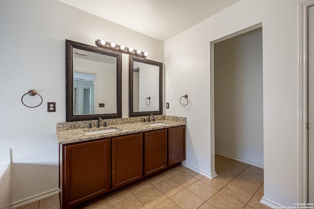 bathroom with double vanity, tile patterned floors, baseboards, and a sink