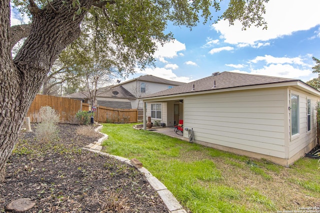 back of house with a patio area, fence, a lawn, and roof with shingles