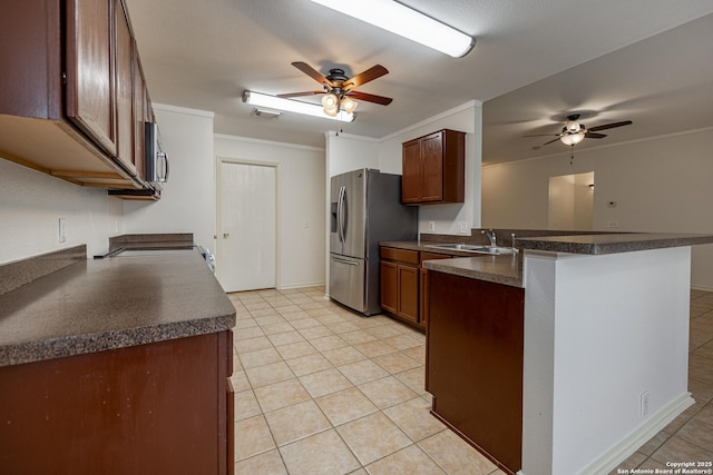 kitchen featuring ornamental molding, a sink, dark countertops, stainless steel appliances, and a peninsula