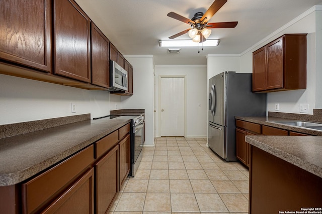 kitchen with dark countertops, ceiling fan, light tile patterned floors, appliances with stainless steel finishes, and a sink