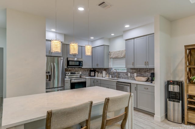 kitchen with visible vents, light countertops, appliances with stainless steel finishes, hanging light fixtures, and tasteful backsplash