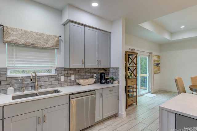 kitchen with gray cabinets, light countertops, dishwasher, and a sink