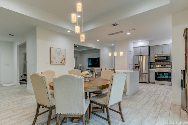 dining room featuring light wood-style flooring, visible vents, and baseboards