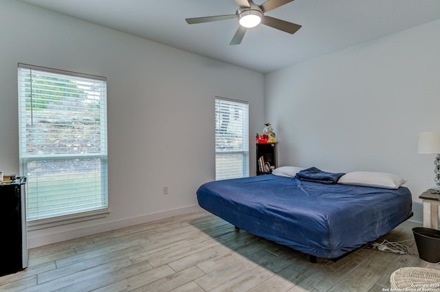 bedroom with light wood-type flooring, baseboards, and a ceiling fan