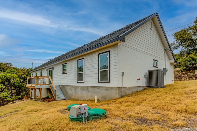 view of side of property featuring a deck, a yard, central AC unit, and stairs