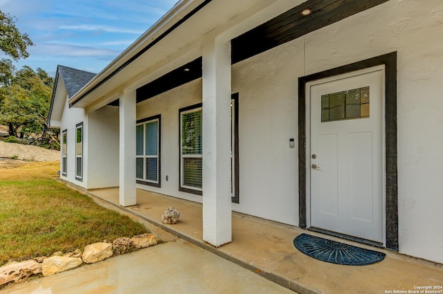 property entrance with roof with shingles and stucco siding