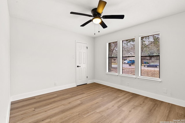 empty room with ceiling fan, light wood-style flooring, and baseboards