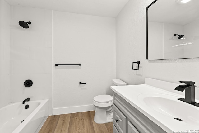 full bathroom with baseboards, toilet, wood finished floors, vanity, and shower / washtub combination