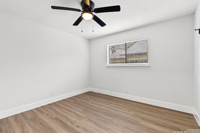 spare room with light wood-type flooring, a ceiling fan, and baseboards