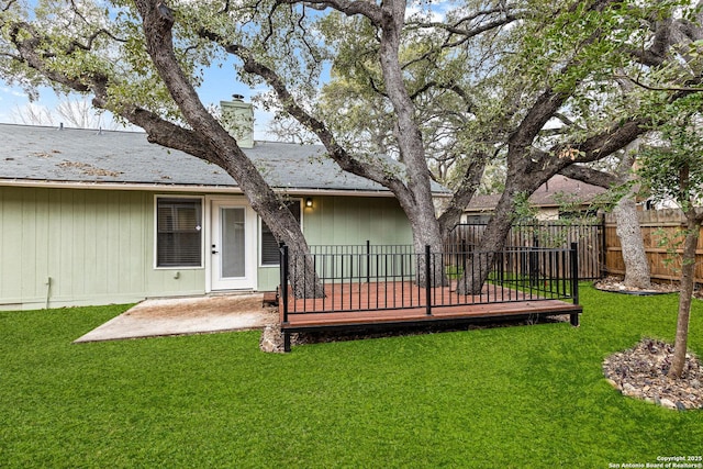 back of house featuring a chimney, fence, a lawn, and a wooden deck