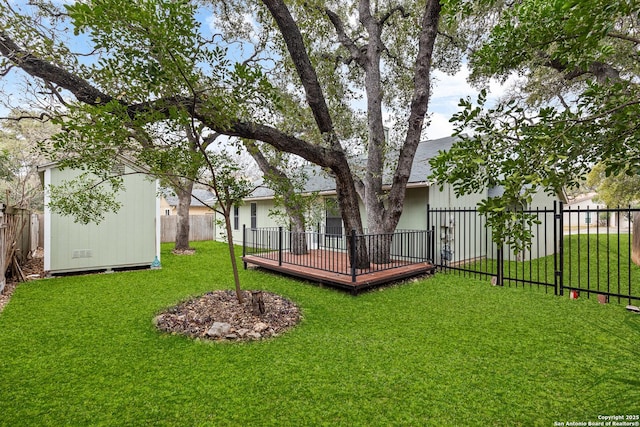 view of yard with a storage shed, a fenced backyard, a deck, and an outbuilding