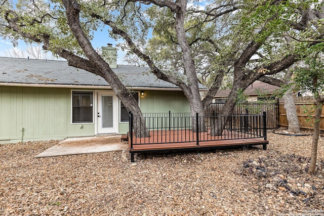 rear view of house with a chimney, fence, and a deck