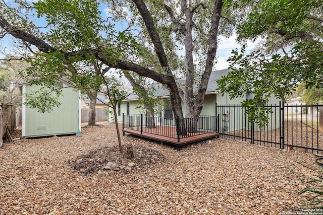 view of yard featuring a wooden deck, a fenced backyard, an outbuilding, and a shed