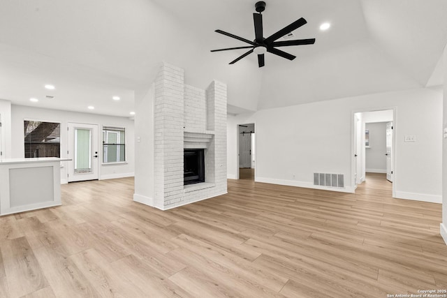 unfurnished living room featuring light wood-type flooring, a brick fireplace, ceiling fan, and visible vents