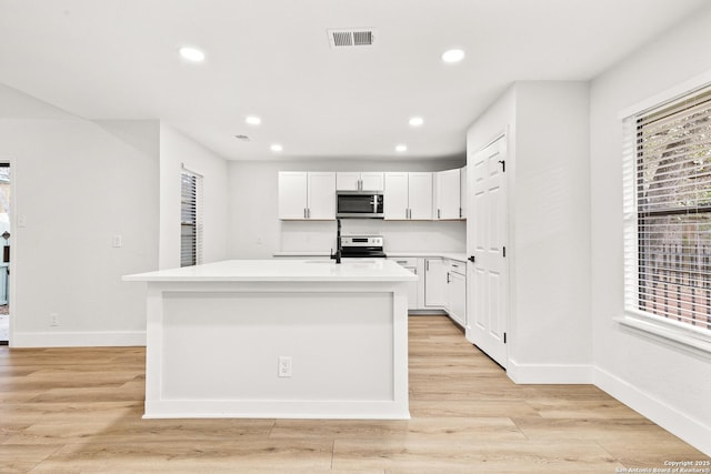 kitchen featuring white cabinetry, a center island with sink, appliances with stainless steel finishes, and light countertops