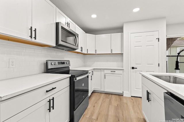 kitchen with white cabinets, light wood-style flooring, stainless steel appliances, a sink, and recessed lighting