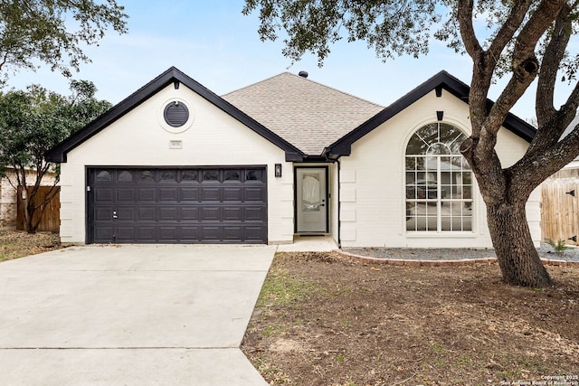 ranch-style house featuring a garage, driveway, a shingled roof, and fence