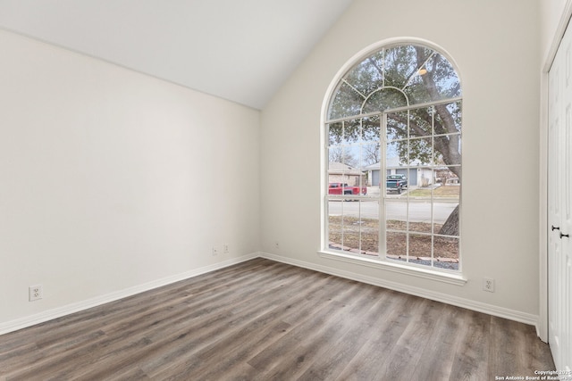 spare room featuring vaulted ceiling, wood finished floors, and baseboards