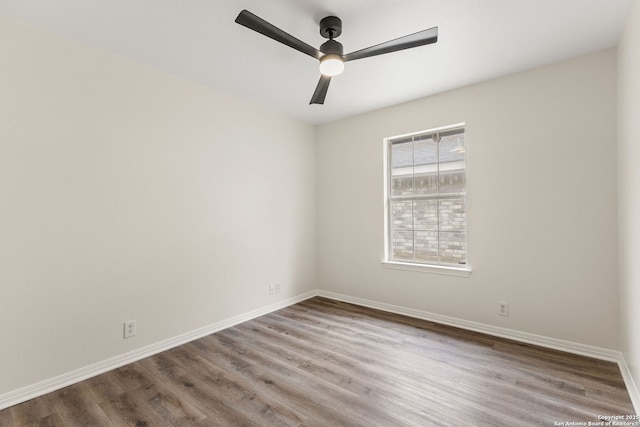 spare room featuring light wood finished floors, a ceiling fan, and baseboards