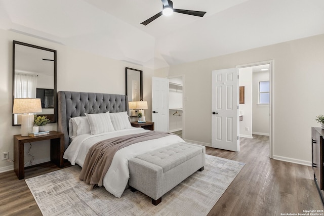 bedroom with a ceiling fan, a spacious closet, baseboards, and wood finished floors