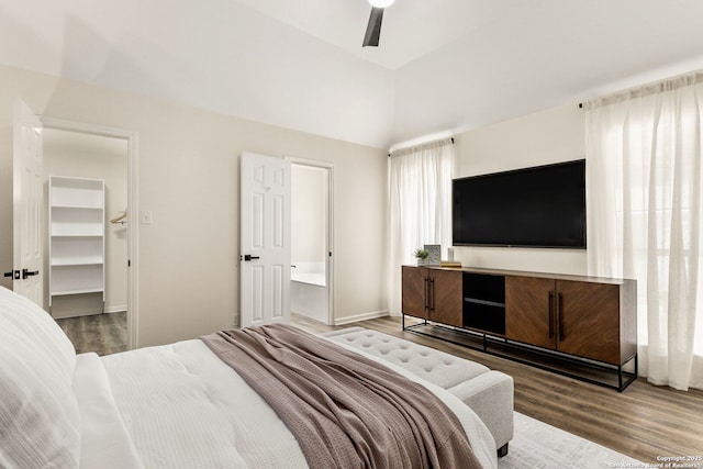 bedroom featuring a ceiling fan, lofted ceiling, a walk in closet, and wood finished floors