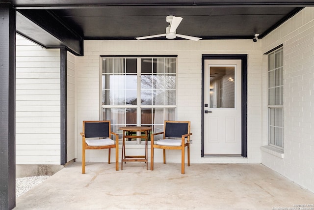 entrance to property with ceiling fan, a patio, and brick siding