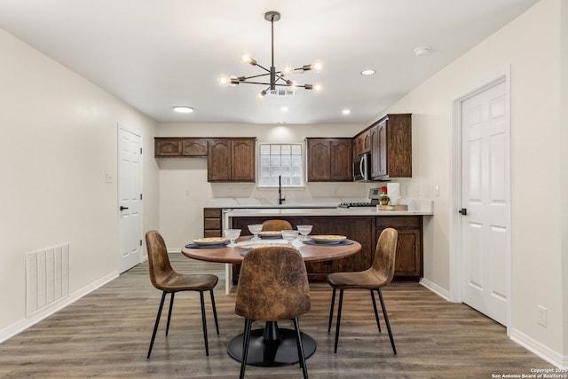 kitchen with a peninsula, dark wood-style flooring, visible vents, light countertops, and stainless steel microwave