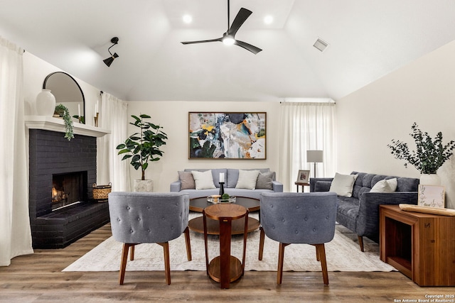 living room with lofted ceiling, a fireplace, visible vents, and wood finished floors