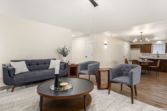 living room with visible vents, light wood-style flooring, and a notable chandelier