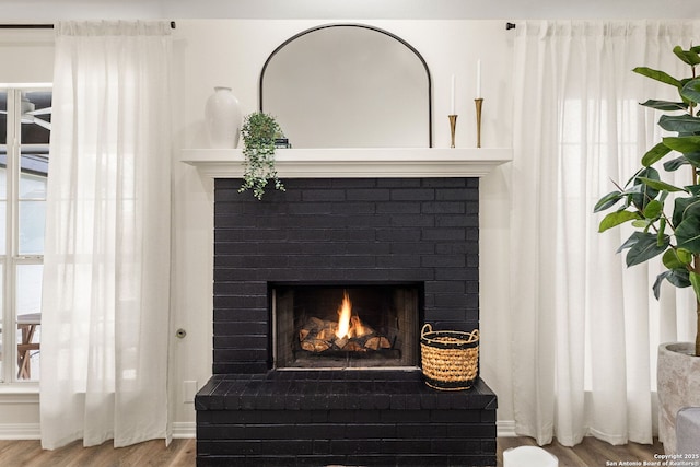 interior details featuring a brick fireplace and wood finished floors