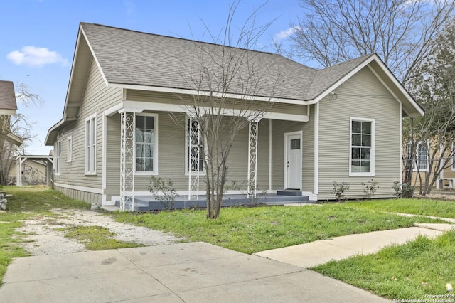 view of front of house with a porch, roof with shingles, and a front lawn